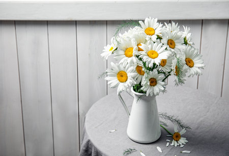 Vase with beautiful chamomile flowers on tableの写真素材