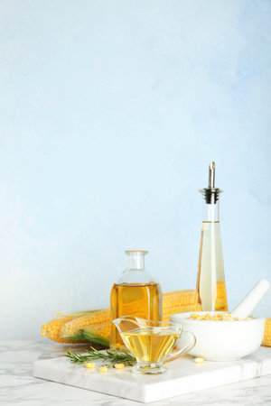 Bottles and gravy boat with fresh corn oil on table against color wallの写真素材