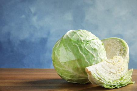 Whole and sliced cabbages on wooden tableの写真素材