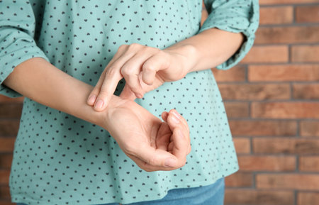 Young woman checking pulse on brick wall backgroundの写真素材
