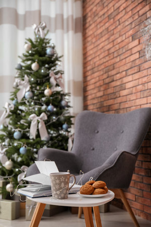 Book with treat on table and Christmas tree in stylish living room interiorの写真素材