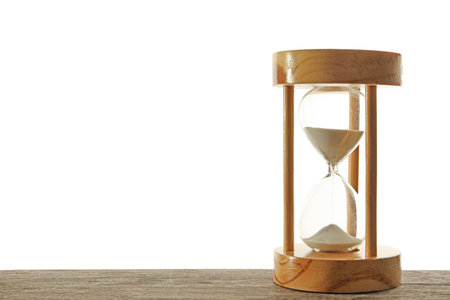 Hourglass with flowing sand on table against light background. time managementの写真素材