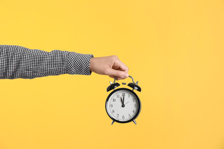 Young woman holding clock on color background. time management