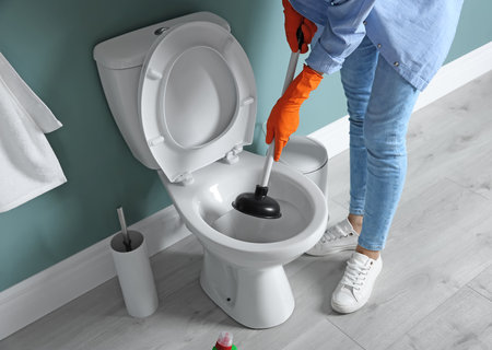 Woman cleaning toilet bowl in bathroomの写真素材