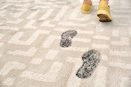 Person in dirty shoes leaving muddy footprints on carpetの写真素材