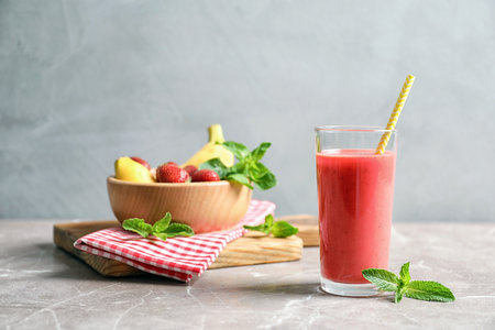 Glass with tasty strawberry smoothie on tableの写真素材