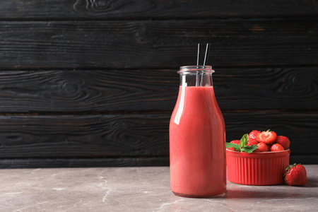 Bottle with tasty strawberry smoothie on tableの写真素材