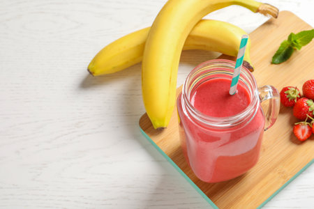 Mason jar with tasty strawberry smoothie on wooden boardの写真素材