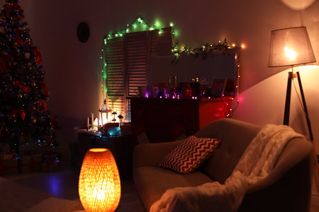 Stylish living room interior with Christmas tree and fairy lights at nightの写真素材