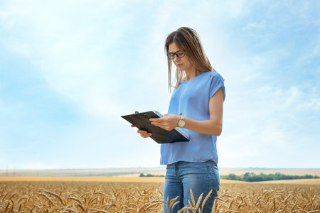 Young agronomist with clipboard in grain field. Cereal farmingの写真素材