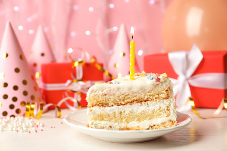 Slice of delicious birthday cake with candle on tableの写真素材