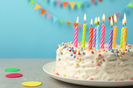 Delicious birthday cake with burning candles on tableの写真素材