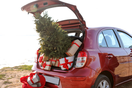 Red car with gift boxes and Christmas tree on the beach. santa claus deliveryの写真素材