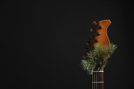 Guitar with fir tree twig on black background. christmas music concept