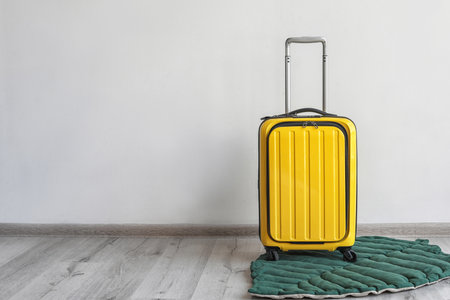 Bright yellow suitcase and leaf shaped rug indoorsの写真素材