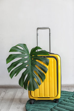 Bright yellow suitcase with tropical leaf indoorsの写真素材