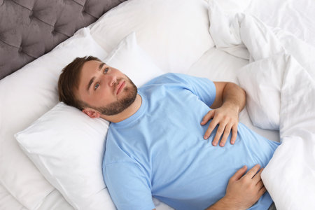 Young man lying in bed at home. Sleep disorderの写真素材