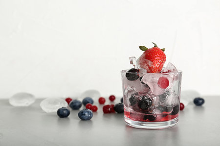 Glass with frozen berries on gray tableの写真素材