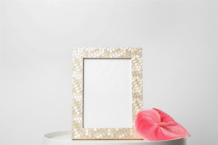 Blank frame and flower on table against white background. Mock up design