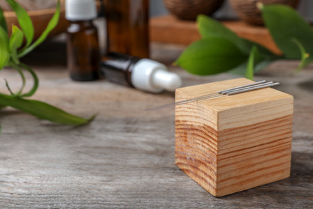 Wooden cube with needles for acupuncture on tableの写真素材