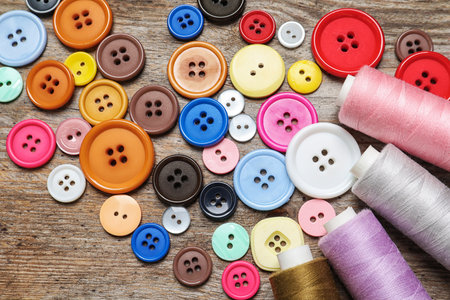 Colorful buttons and threads on wooden background, top view. tailoring equipment