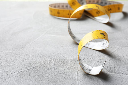 Measuring tape on gray background, closeup. tailoring equipmentの写真素材