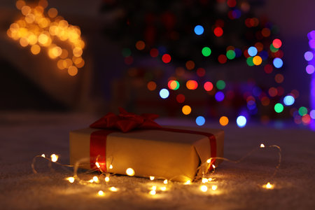 Gift box and electric garland on floor. Stylish Christmas interiorの写真素材