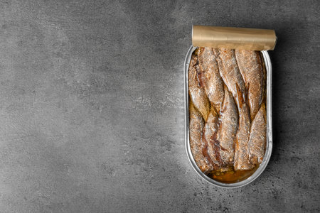 Tin can with canned fish on gray background, top view