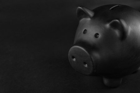 Black piggy bank on table against dark backgroundの写真素材