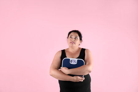 Overweight woman in sportswear with scales on color backgroundの写真素材