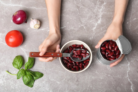 Woman with tin can of conserved beans at table, top viewの写真素材