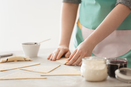 Woman preparing tasty croissants with chocolate paste on table, closeupの写真素材