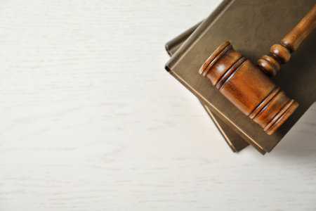 Wooden gavel and books on light table, top view. law concept