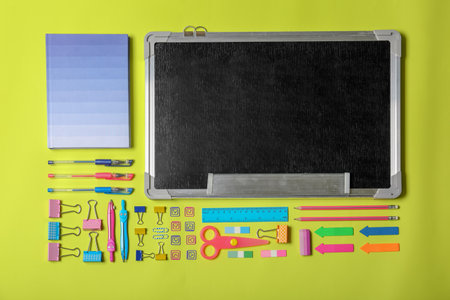 Flat lay composition with different school stationery and small chalkboard on color background
