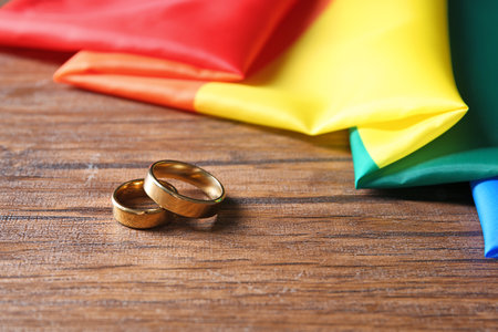 Wedding rings and rainbow flag on wooden table. gay marriageの写真素材