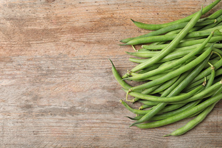 Fresh green French beans on wooden table