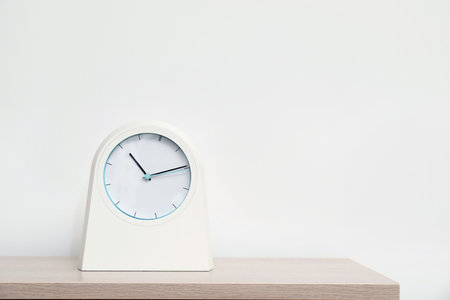 Modern clock on table against light background. time concept