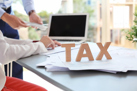 Word TAX and blurred accountants on backgroundの写真素材