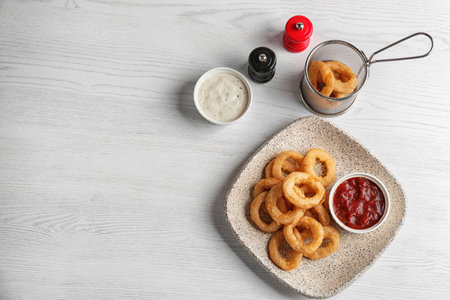 Plate with tasty onion rings and sauces on table, top viewの写真素材