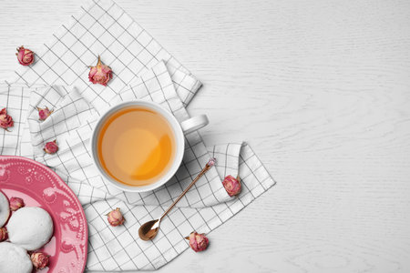 Flat lay composition with hot tea, meringues and flowers on tableの写真素材
