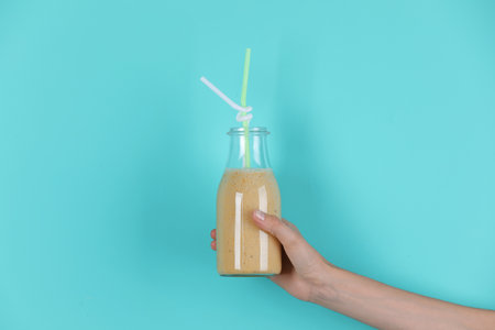 Young woman holding bottle of healthy smoothie on color backgroundの写真素材