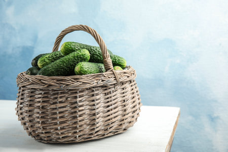 Wicker basket with ripe fresh cucumbers on tableの写真素材