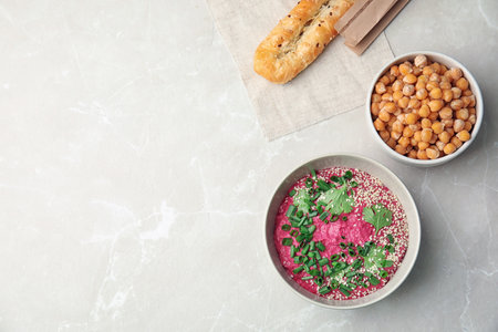 Flat lay composition with bowl of tasty beet hummus, bread and chickpea on light tableの写真素材