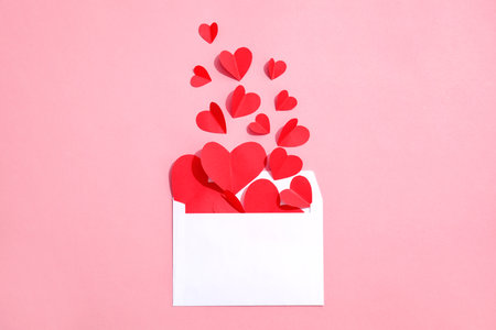 Envelope with small paper hearts on color background, top view