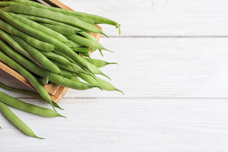 Wooden crate with fresh green French beans on table