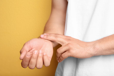 Young man checking pulse on color backgroundの写真素材