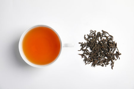 Cup of delicious tea with dried leaves on light background, top viewの写真素材