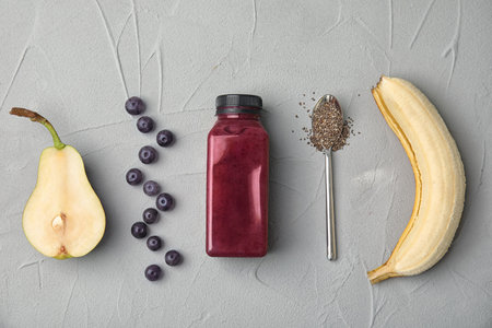 Flat lay composition with ingredients for delicious acai cocktail and bottle of juice on gray tableの写真素材