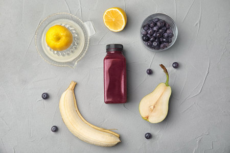 Flat lay composition with ingredients for delicious acai cocktail and bottle of juice on gray tableの写真素材
