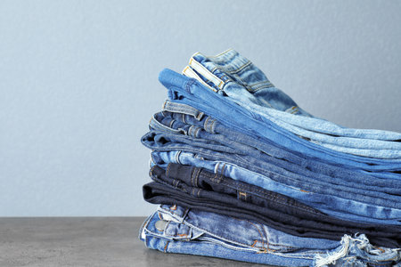 Stack of jeans on table against gray backgroundの写真素材
